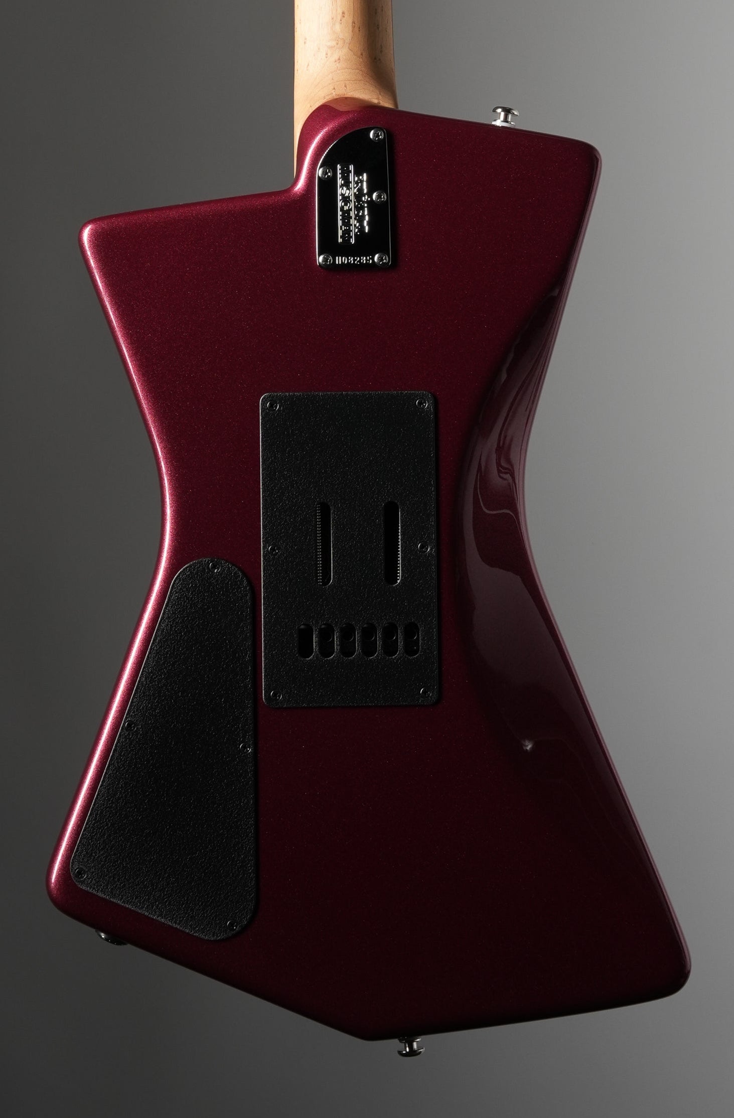 Glossy red electric guitar with a wooden neck on a gray background
